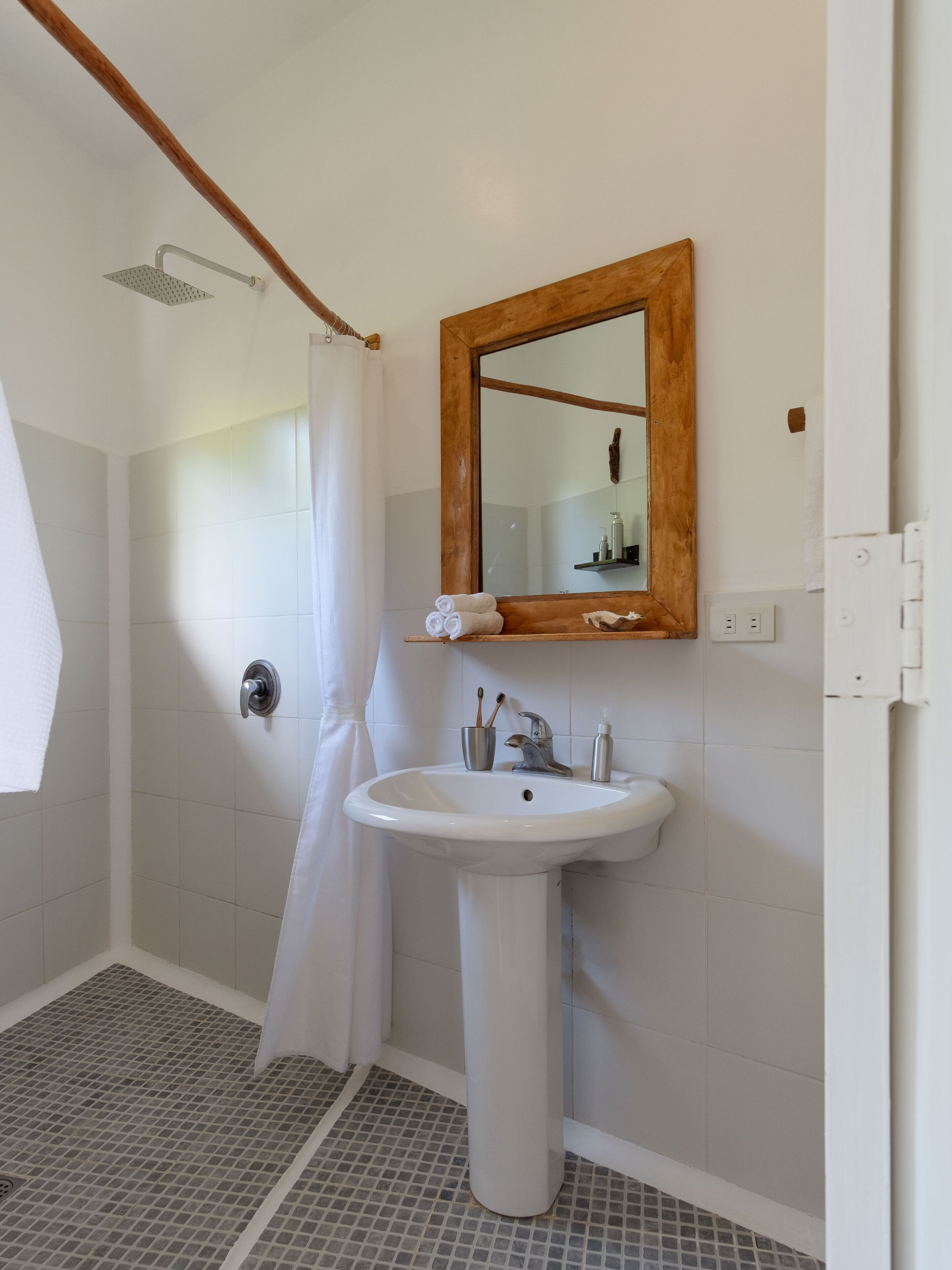 Un bagno con doccia, lavandino e specchio.