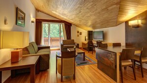 A spacious living area with a wooden ceiling, a television, a dining table with chairs, and a sofa.