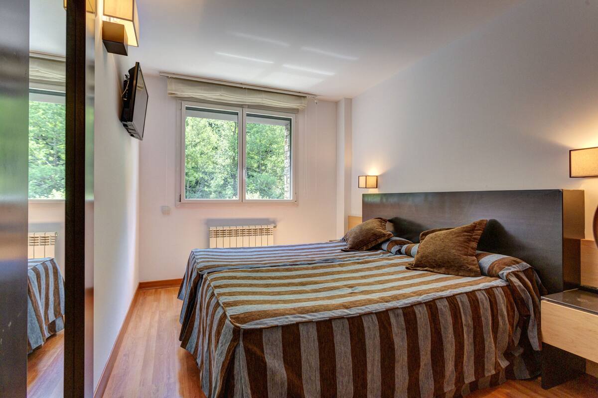 Une chambre avec deux lits, une grande fenêtre et des lampes de chevet.