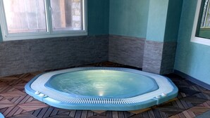 A hot tub in a room with a geometric patterned floor and a window with a view.