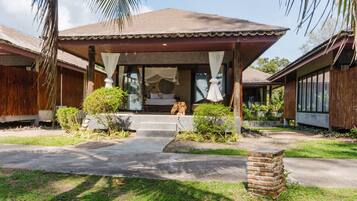 A bungalow with a covered porch, a bed with a canopy, and a small garden area.