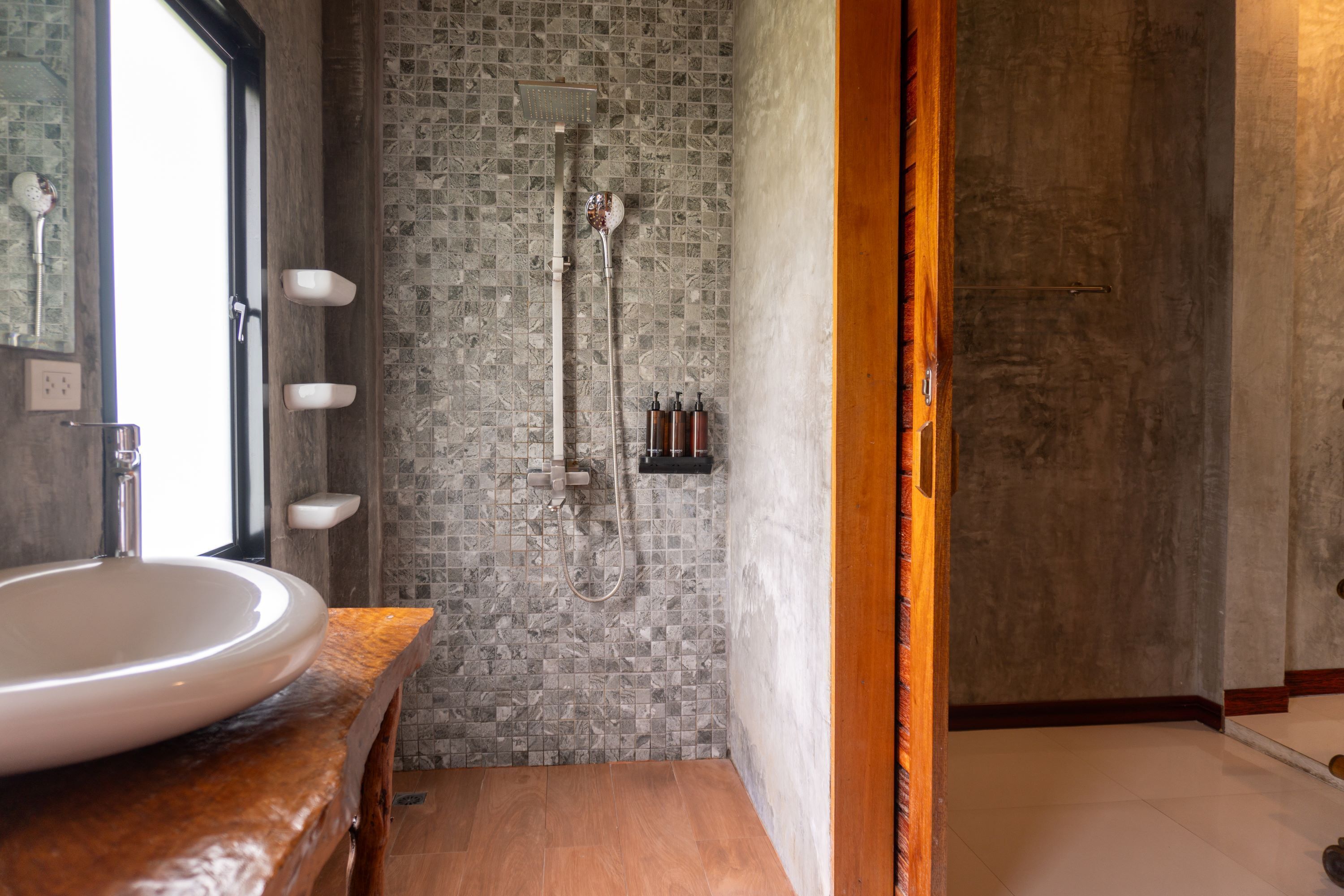 A bathroom with a large sink, a shower with a rain showerhead, and a tiled wall.