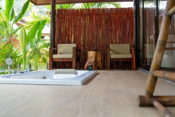 Un área de spa con una bañera grande, dos sillones y una mesa de madera.