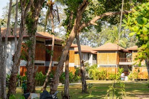 Un resort con varias edificaciones de madera, rodeado de exuberante vegetación y palmeras.