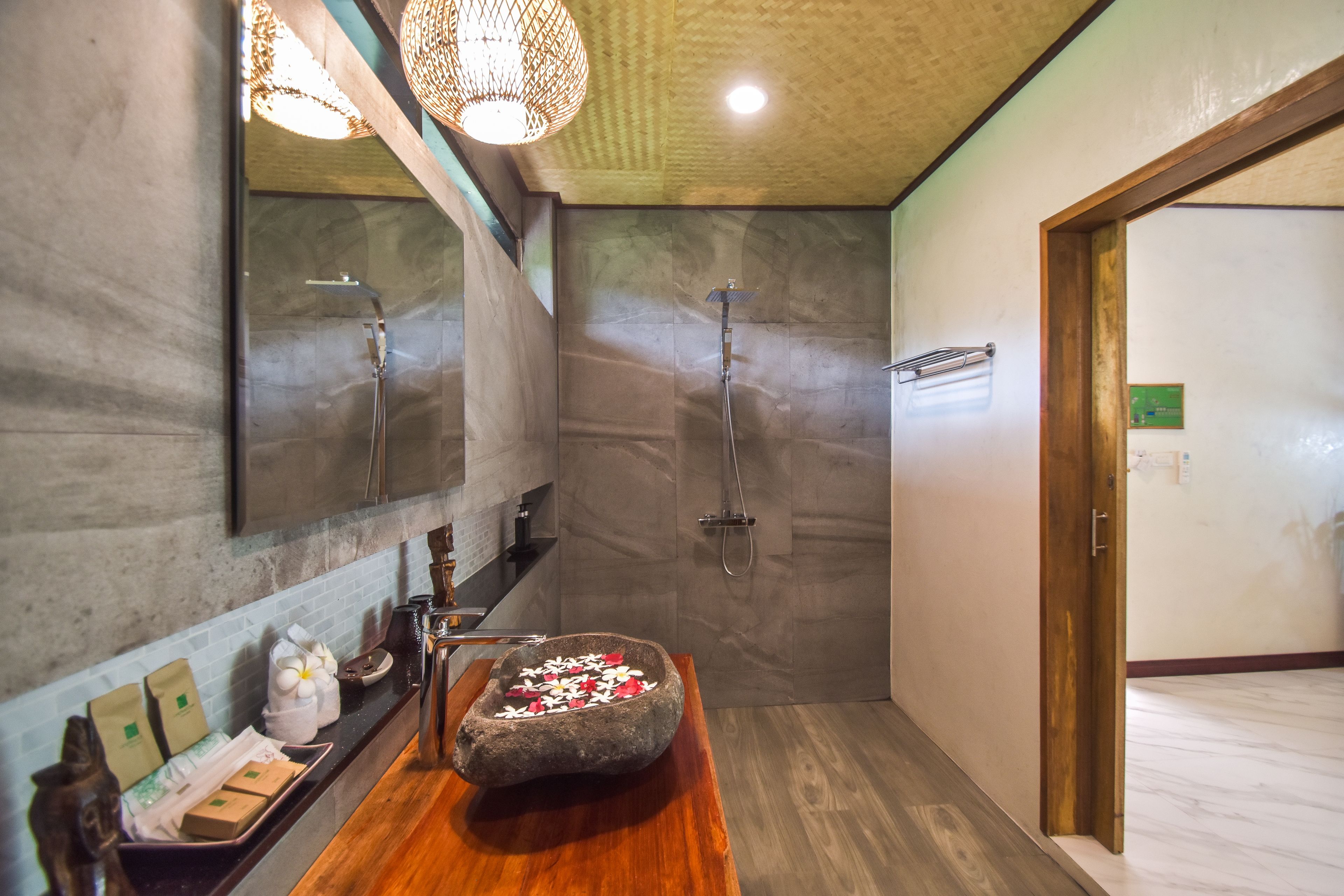 Ein modernes Badezimmer mit einem Becken aus Stein, zwei Duschen und einem Holzkosmetikschrank.