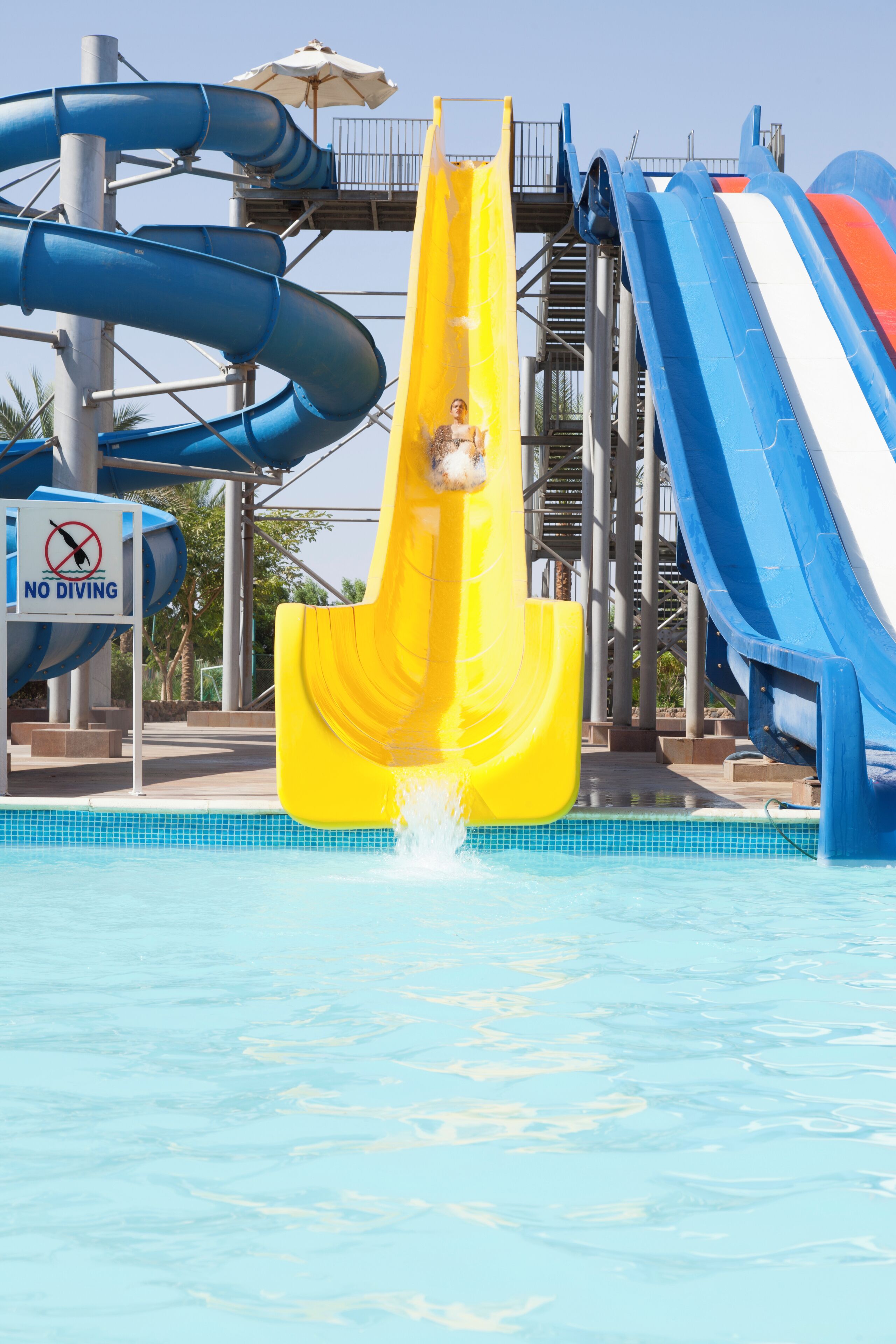 A water park with multiple slides, including a yellow slide, and a 'No Diving' sign.
