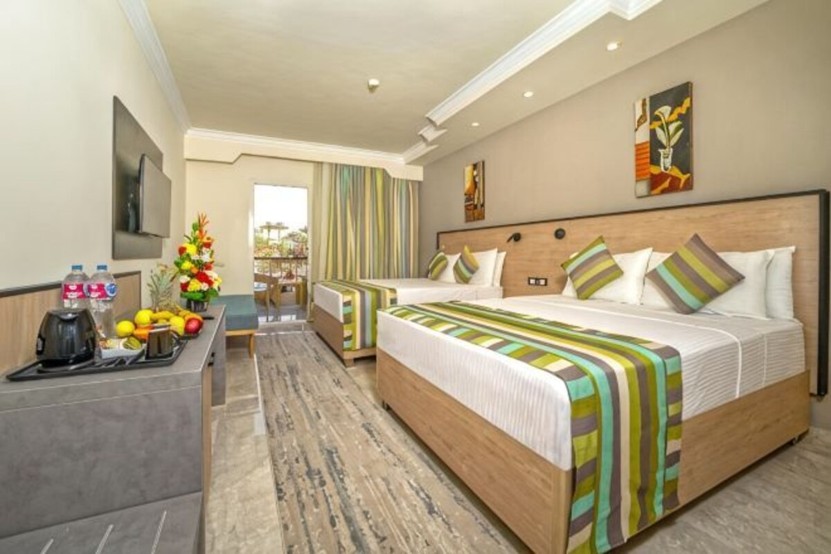 A hotel room with a large bed, a desk with a coffee maker, and a view of the outdoors.