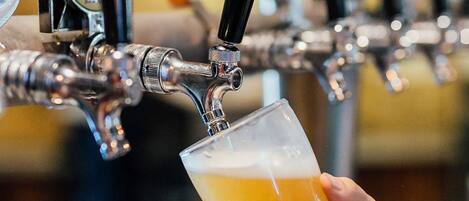 Una mano sosteniendo una jarra de cerveza en un grifo.