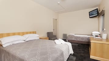 Una habitación de hotel con dos camas, un escritorio, una silla, un televisor y una ventana.
