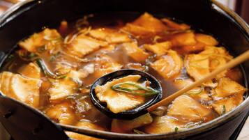 A close-up of a hot pot dish with tofu and vegetables in a black pot.