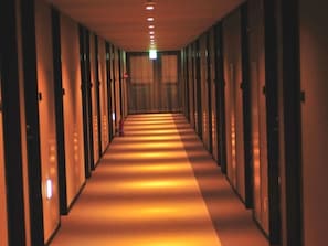 A long, narrow hallway with doors on both sides, leading to individual rooms.