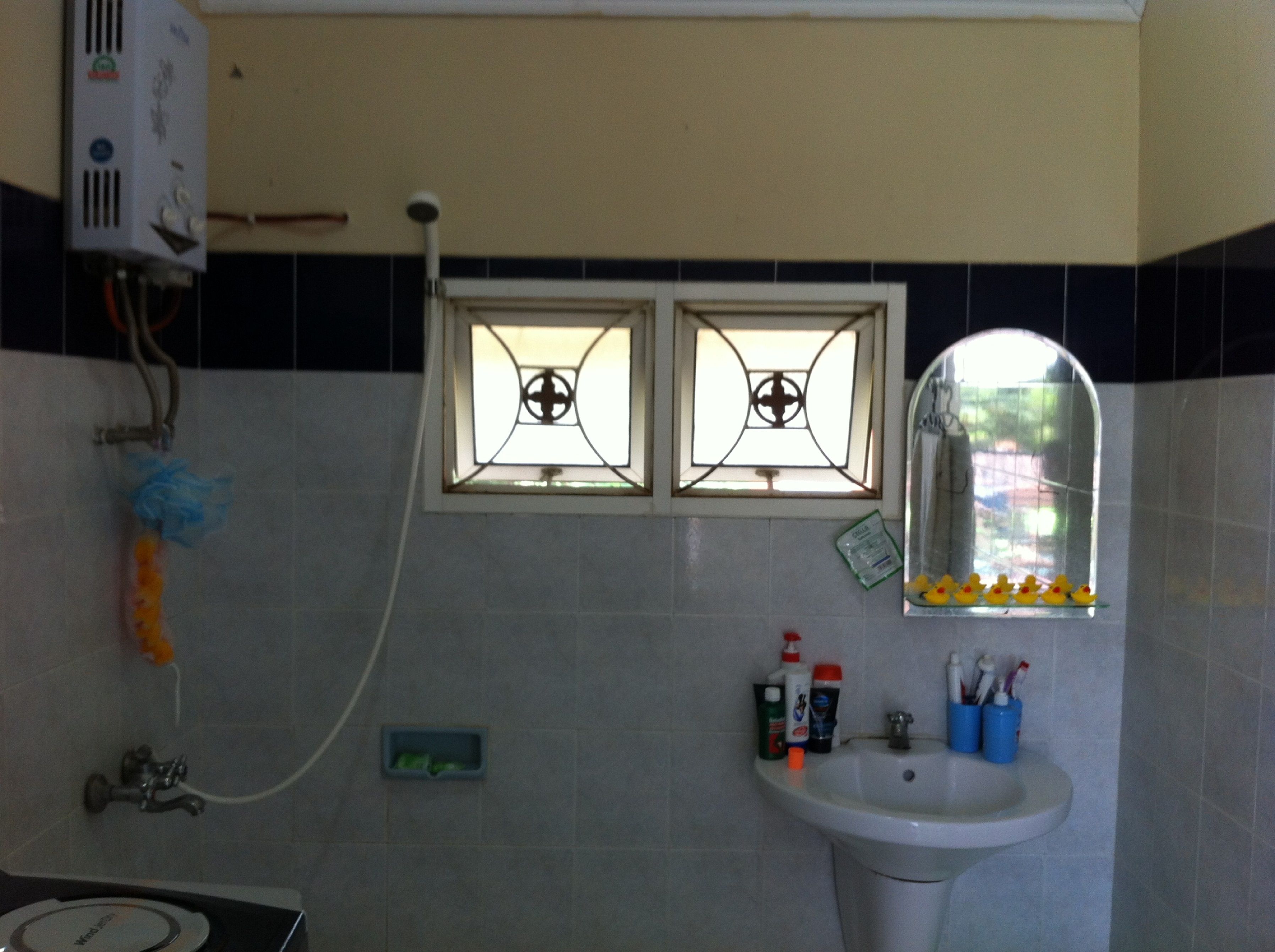 A bathroom with a sink, two windows with decorative glass, a shower, and a mirror.