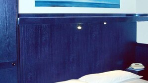A bedroom with a bed, a nightstand, a telephone, and a painting of a blue sky. - Hotel Residence D'Azeglio (Turin)