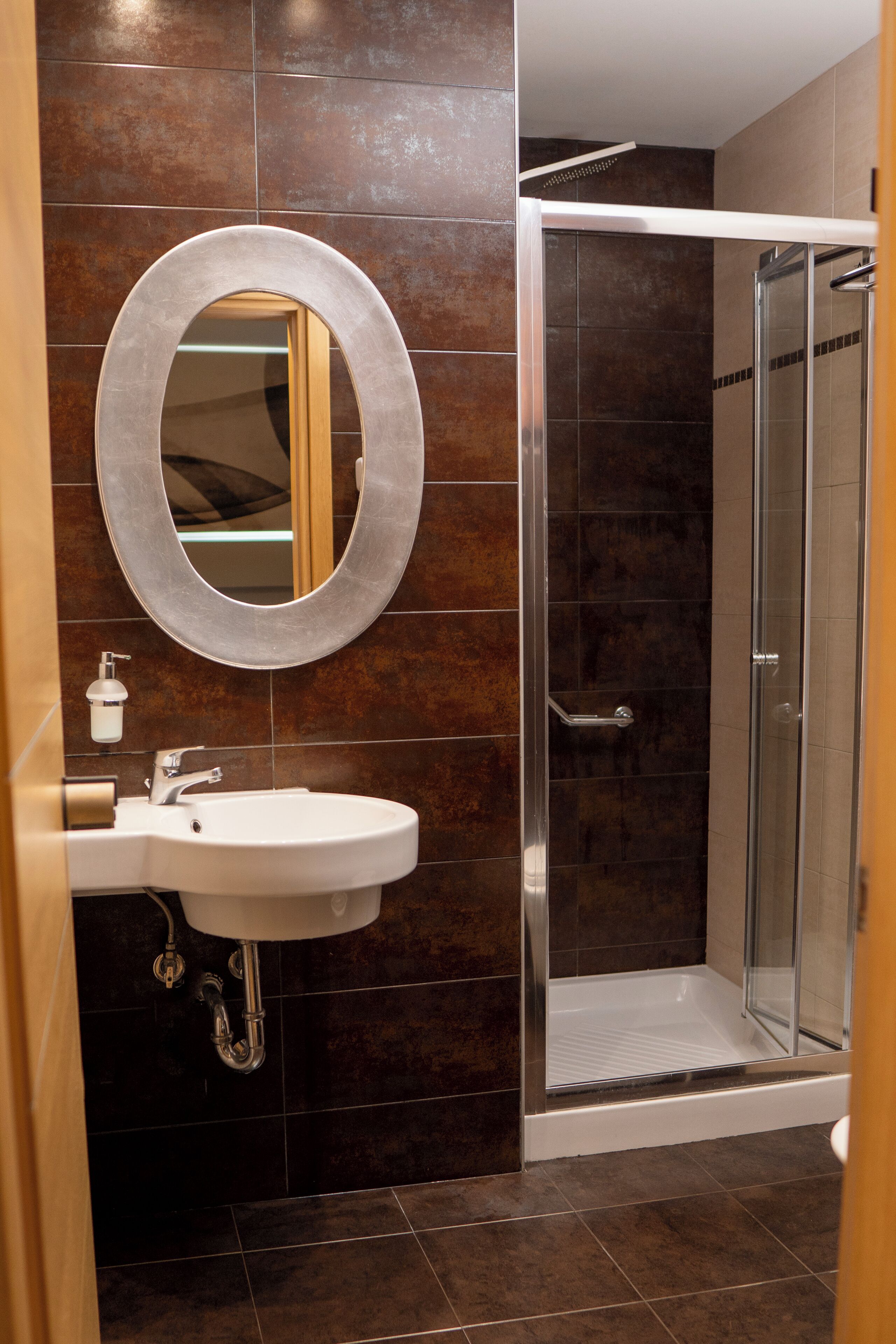 A bathroom with a sink, mirror, and shower.