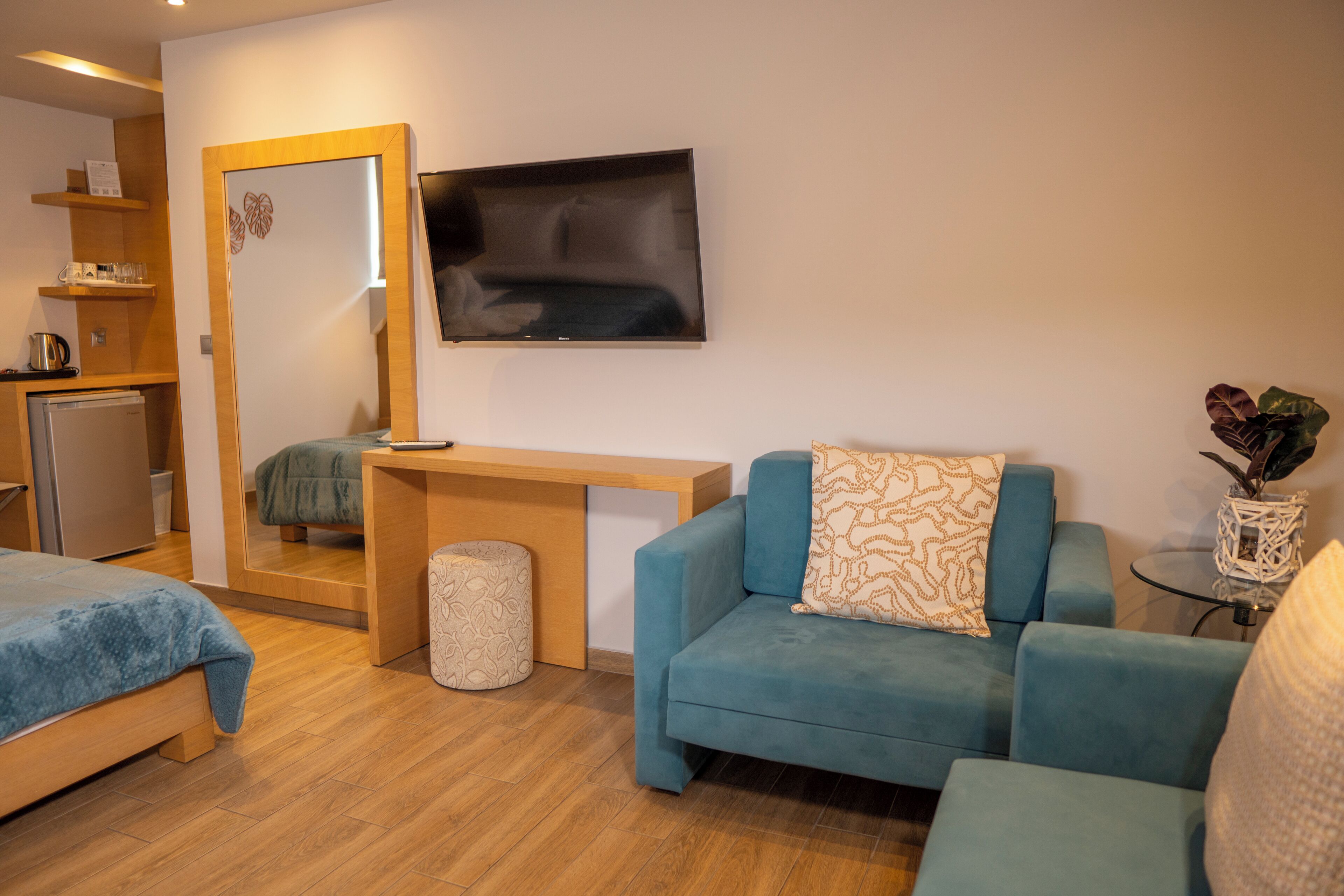 A hotel room with a bed, a sofa, a small table, a TV, and a mirror.