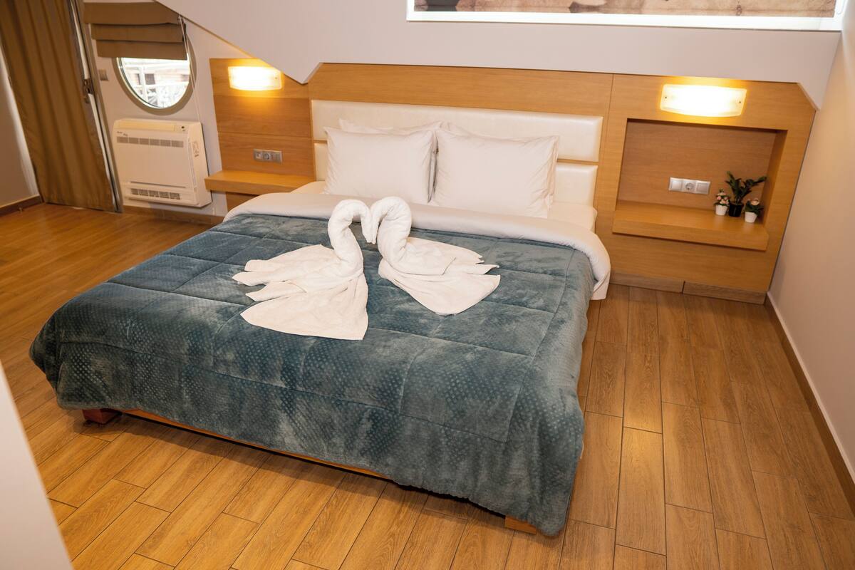 Ein Hotelzimmer mit Bett, Holz-Kopfteil, Nachttisch und Wand-Klimaanlage.