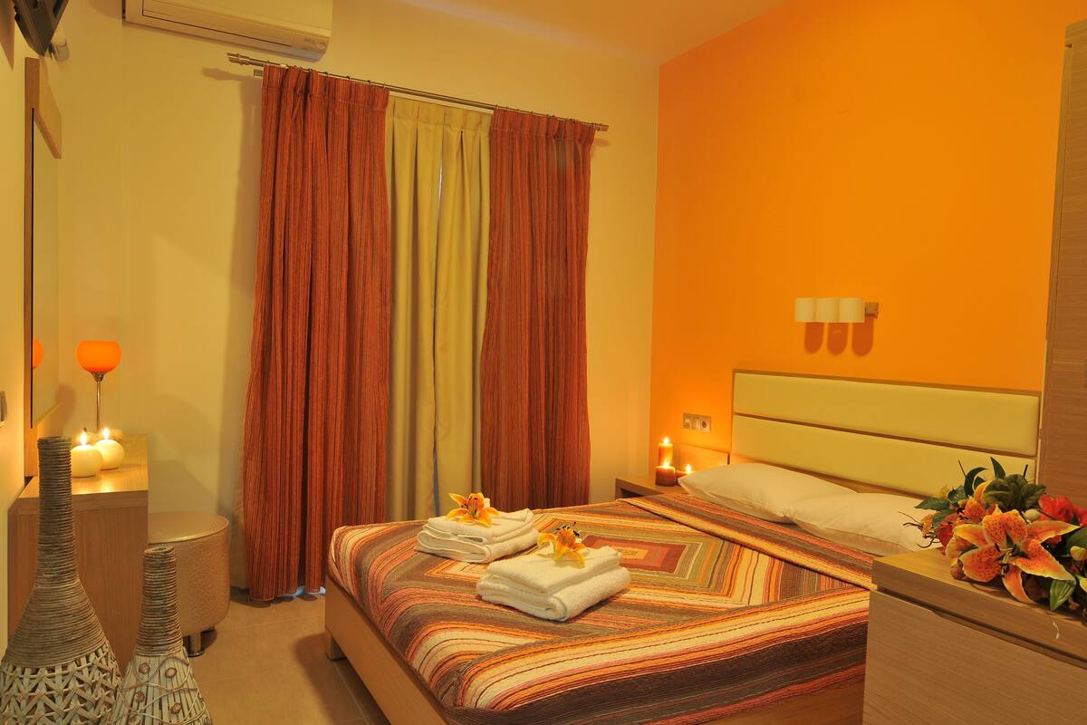 Ein Hotelzimmer mit Bett, Vorhängen, Nachttisch, Lampe und einer Vase.