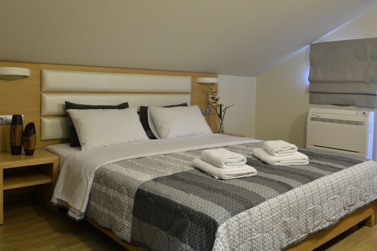 A neatly made bed with a striped bedspread, a bedside table with a lamp, and a wall-mounted air conditioner.