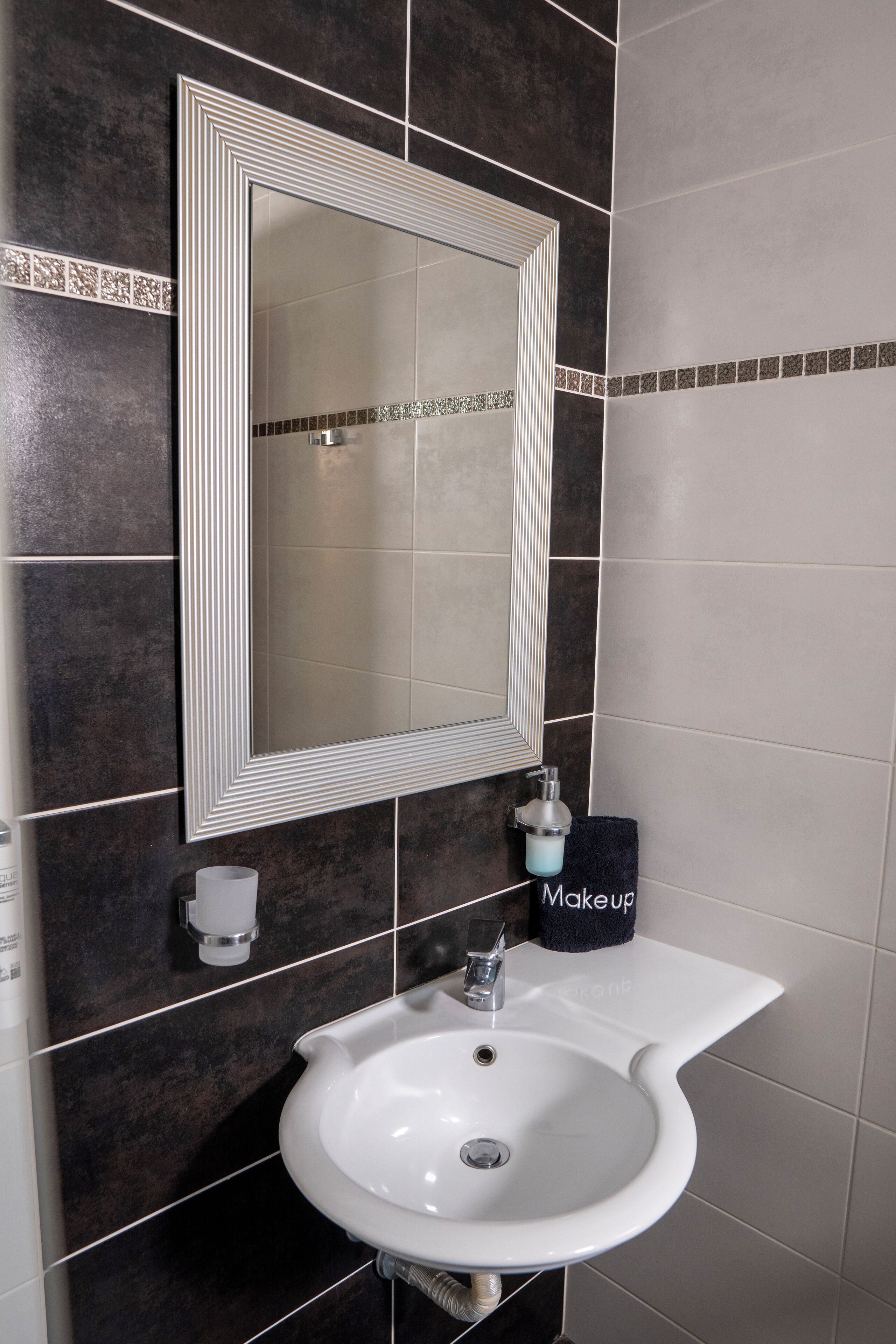 A bathroom with a white sink, a large mirror, and a towel rack.