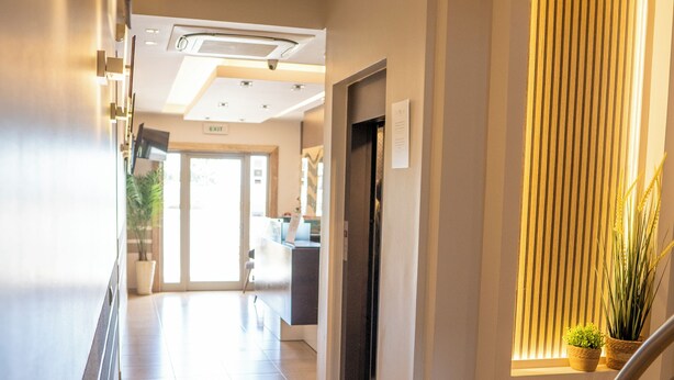 A hotel corridor with a modern design, including a staircase, a reception area, and a potted plant. - Hotel Epavlis Eleftheriadi (Katerini)