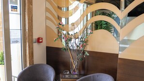 A reception area with two grey armchairs, a vase with flowers, and a modern wall design. - Hotel Epavlis Eleftheriadi (Katerini)