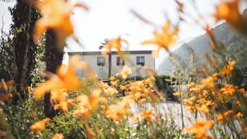 A building with a flat roof, surrounded by greenery and hills.