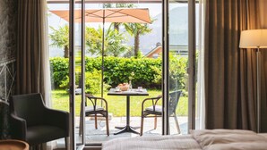 Habitación de hotel con cama, una silla y una mesa con sombrilla fuera de una puerta corrediza de vidrio.
