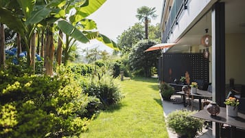 A well-maintained outdoor patio area with a grassy lawn, potted plants, and outdoor furniture.