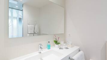 Un baño moderno con un espejo grande, lavamanos blanco y un perchero para toallas.