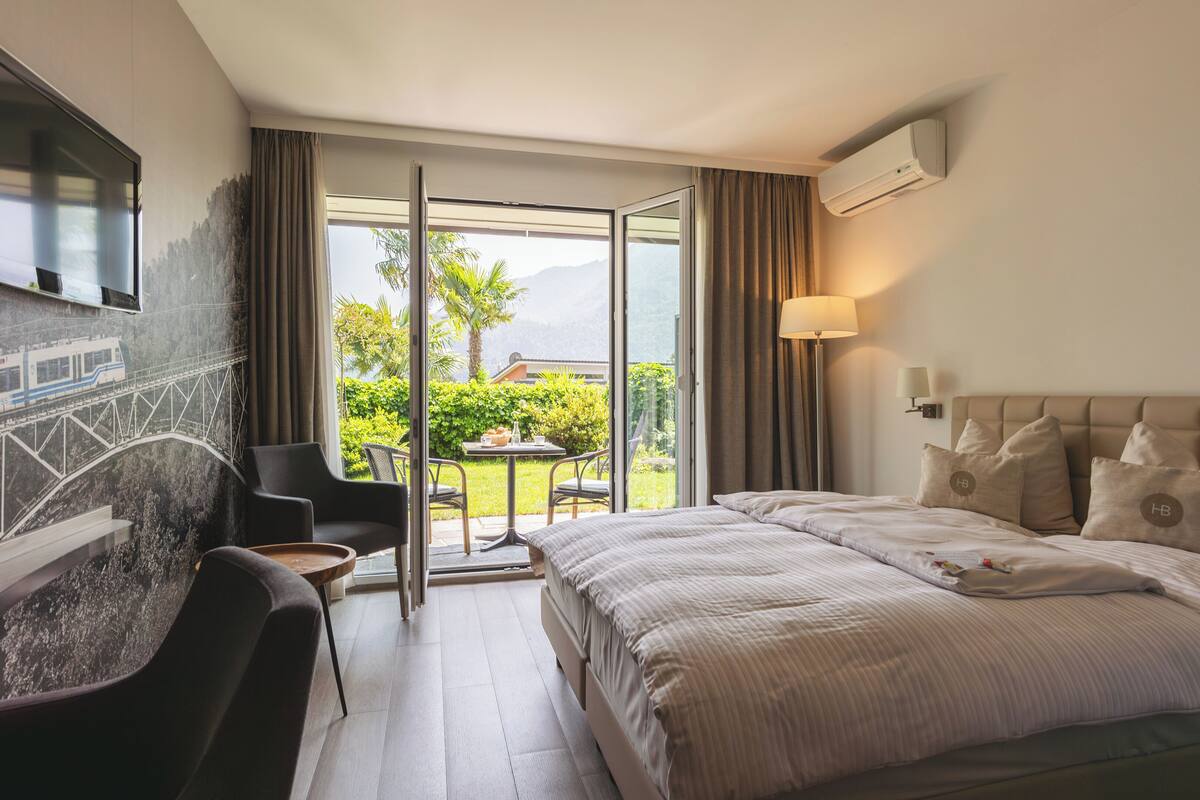 Habitación de hotel con cama, televisor montado en la pared, escritorio y una silla.