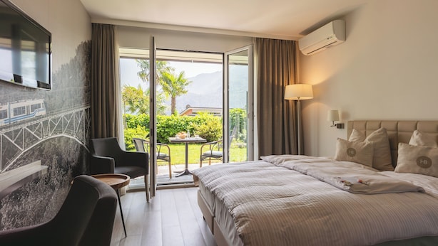 Habitación de hotel con cama, televisor montado en la pared, escritorio y una silla.