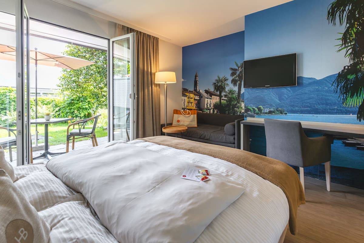 Habitación de hotel con cama, escritorio, televisión y vista a un cuerpo de agua.