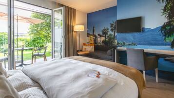 Een hotelkamer met een bed, een bureau, een televisie en uitzicht op een waterpartij.