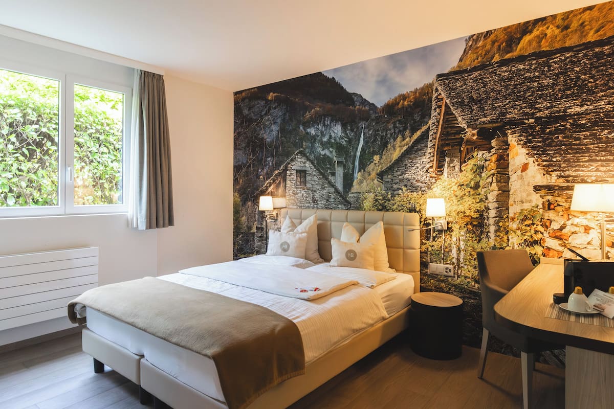 Un dormitorio con una cama grande, un escritorio y un mural de una escena de montaña.