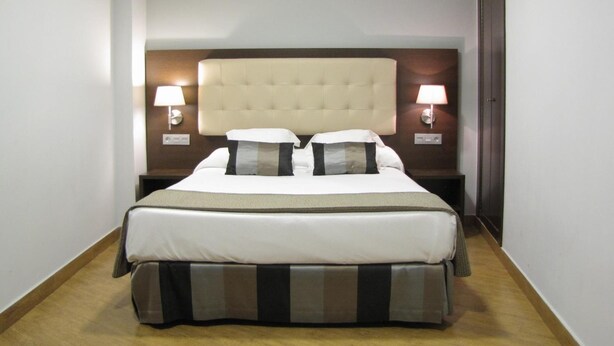Een hotelkamer met een groot bed, twee bedlampen en een houten vloer.