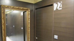 Hotelkamer met een grote spiegel, een houten deur en een nummerbord dat kamer 22 aangeeft.