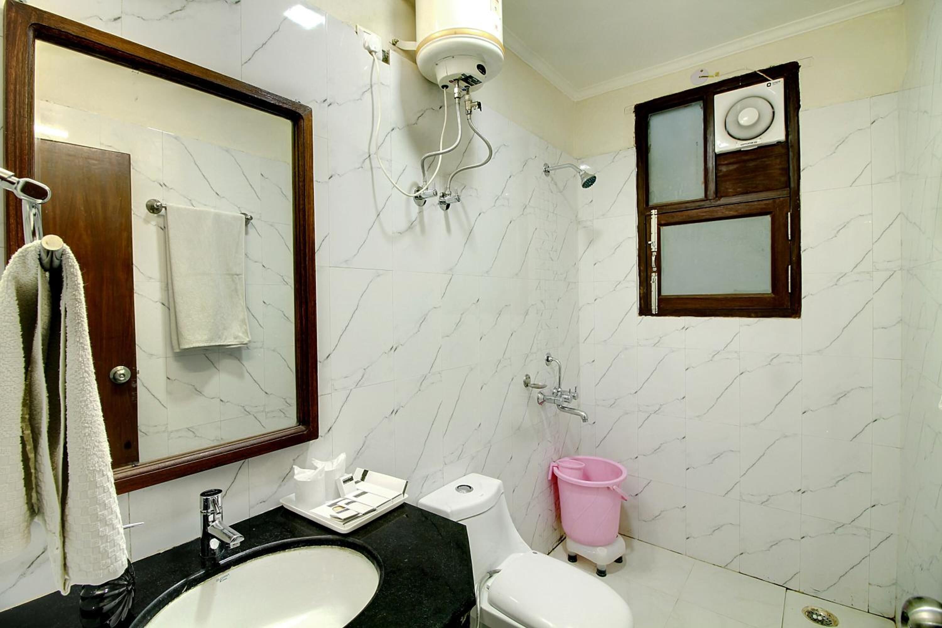 Une salle de bain avec un mur en marbre, un lavabo, des toilettes et une douche.