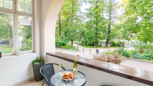 A balcony with a table, chairs, a bottle of wine, and a plate of food. - Apartments Happy Hours (Sopot)