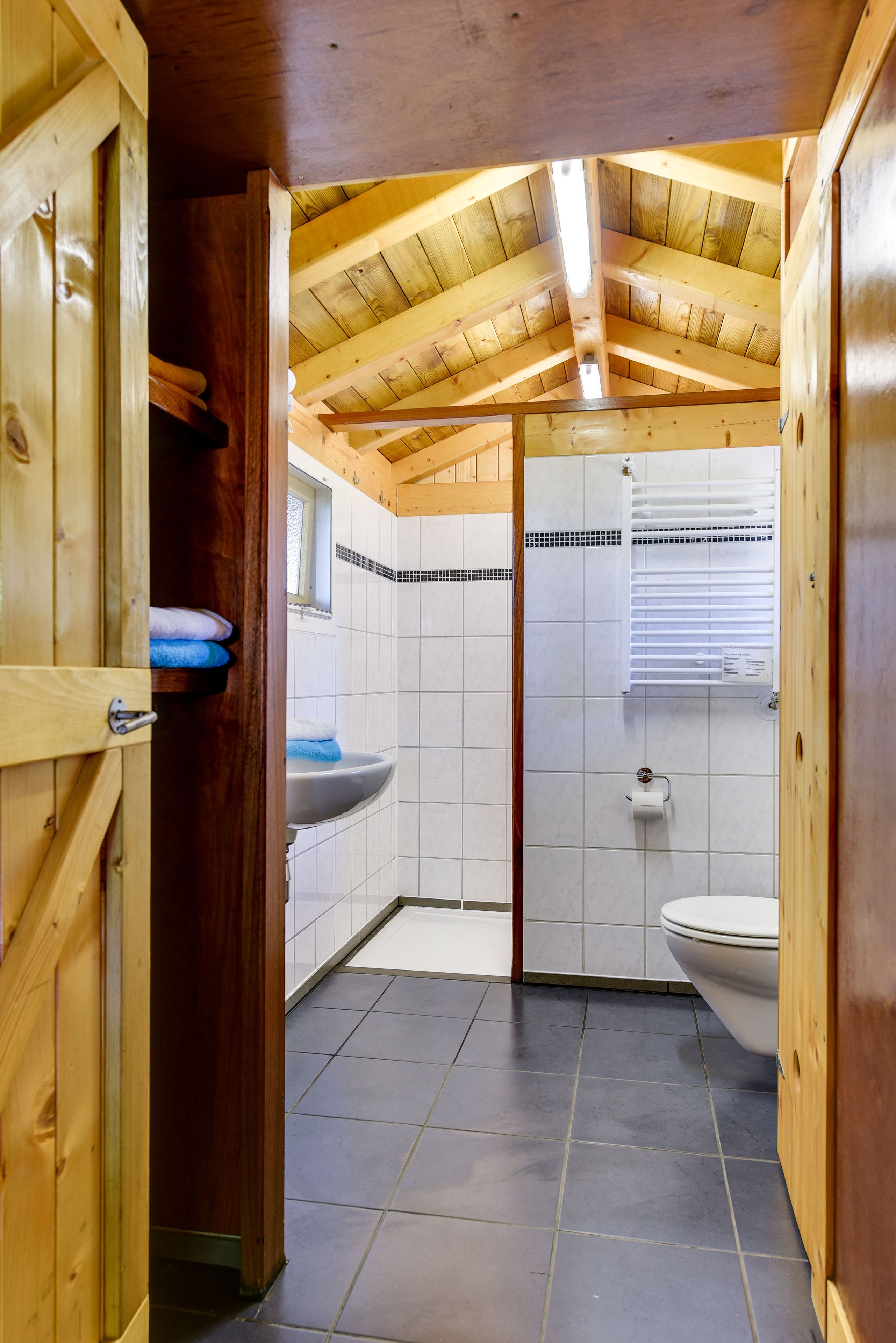 Interior de madera con baño que incluye un lavamanos, inodoro y paredes con azulejos.