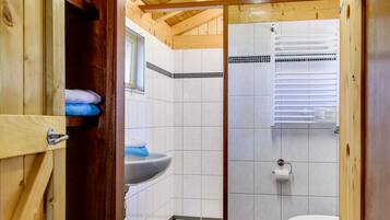Interior de madera con baño que incluye un lavamanos, inodoro y paredes con azulejos.