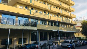A multi-story building with balconies, large windows, and a covered entrance area. - Hotel Beverly (Rimini)