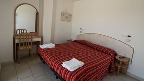 A bedroom with a bed, a desk, a chair, a mirror, and a small bedside table. - Hotel Beverly (Rimini)