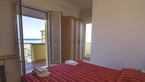 A hotel room with a bed, a desk, and a view of the ocean. - Hotel Beverly (Rimini)