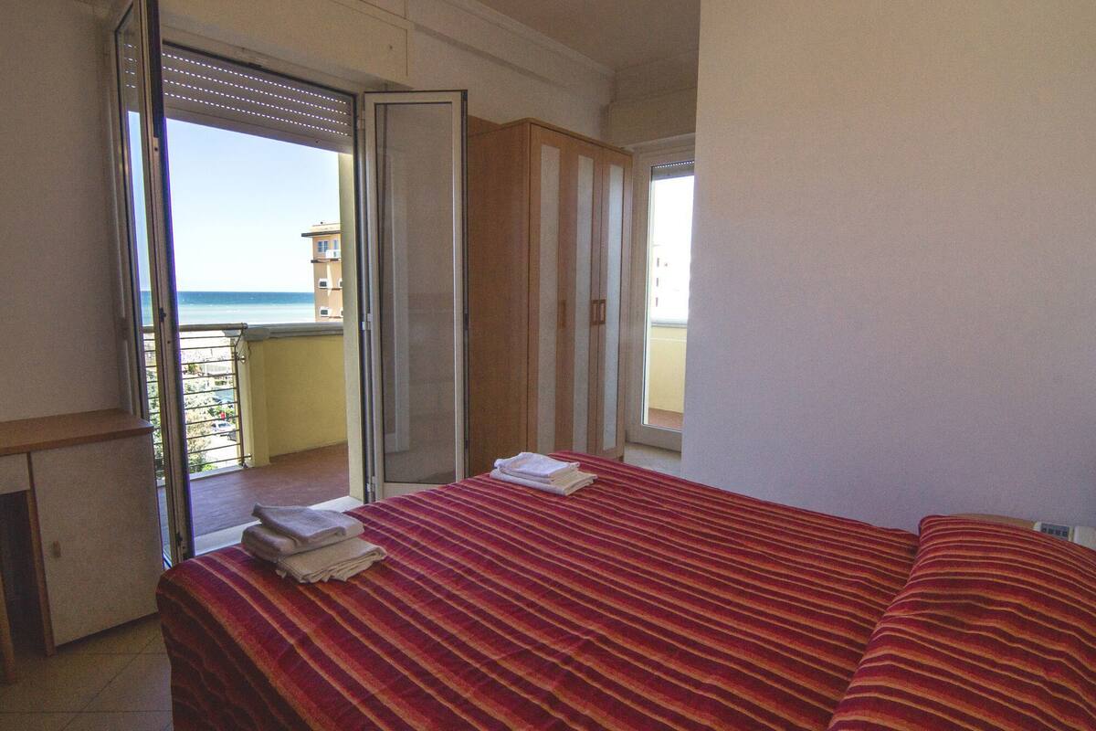 A hotel room with a bed, a desk, and a view of the ocean.