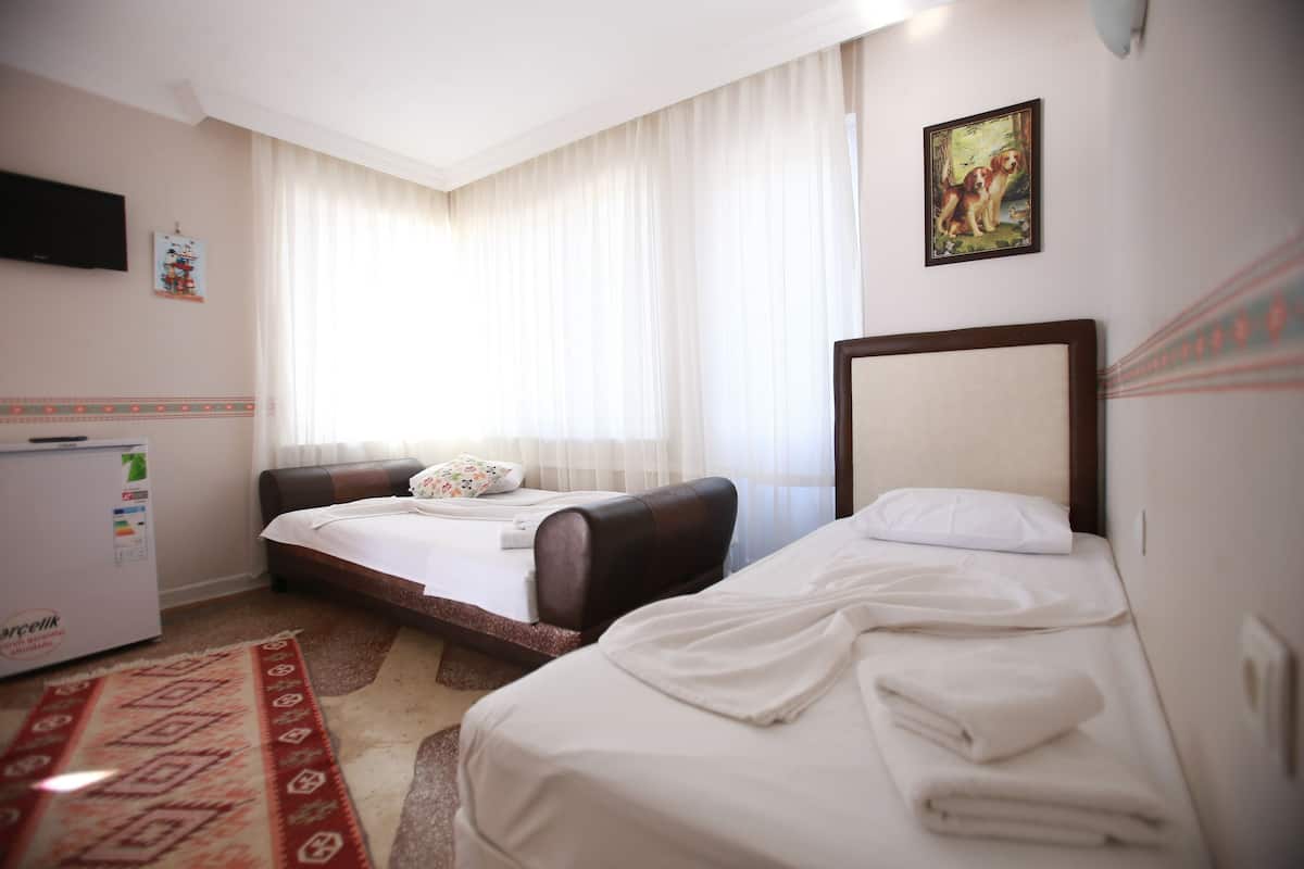 Une chambre d’hôtel avec deux lits, un canapé, une télévision et un réfrigérateur.