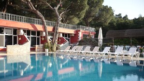 A swimming pool with lounge chairs, a statue, and a building with a red facade.
