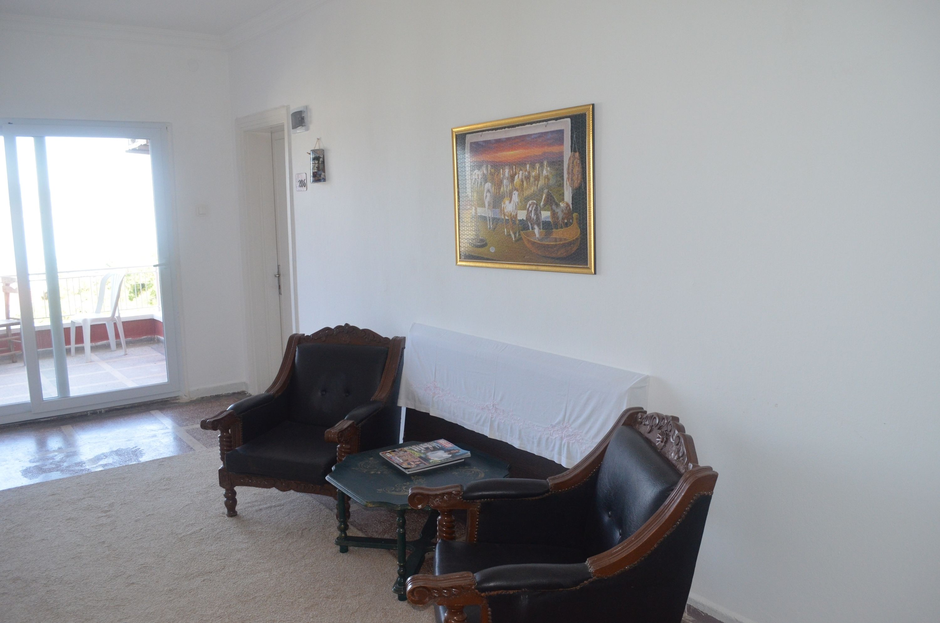 A living room with a dark brown sofa, a small table, and a painting on the wall.