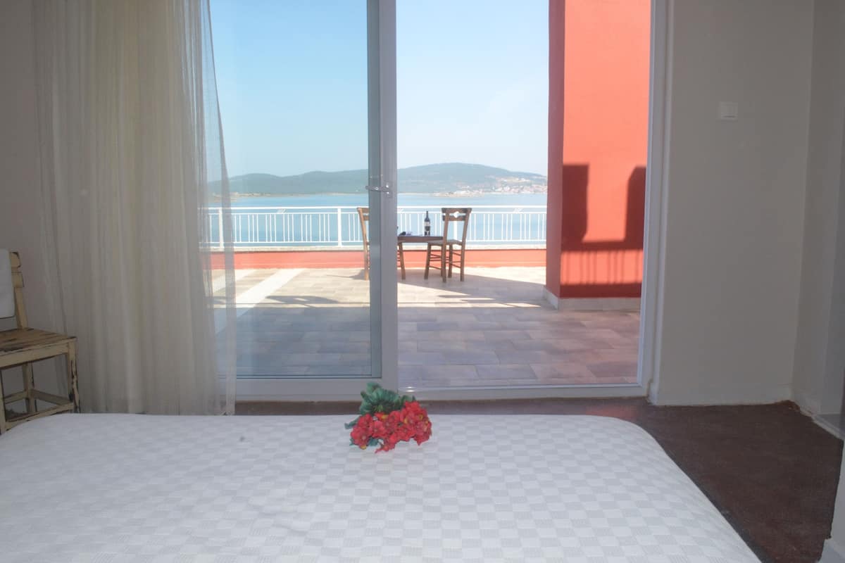 Une chambre d’hôtel avec un lit, une chaise et une vue sur un balcon doté d’une balustrade et d’une table.