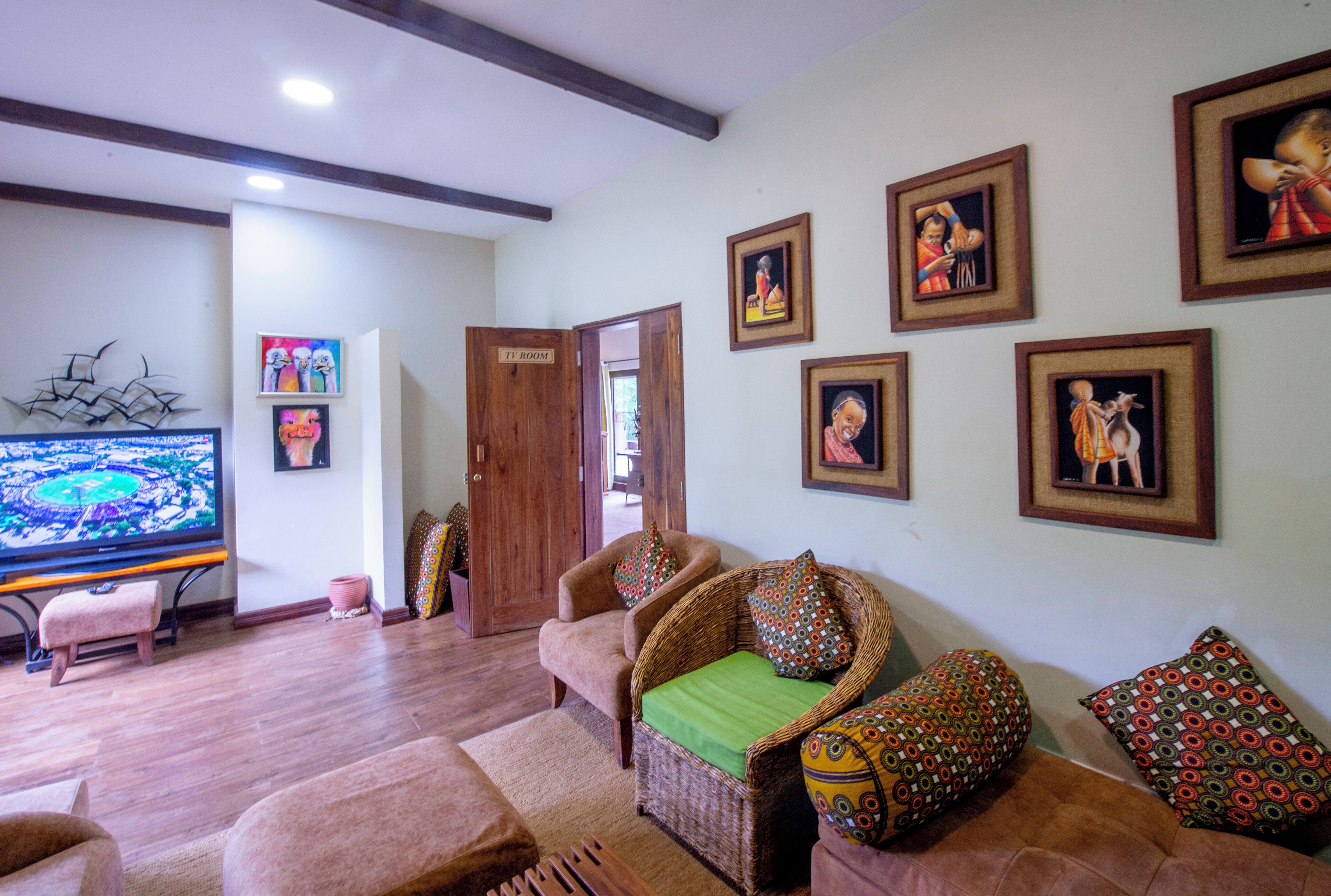 A living room with a television, wicker furniture, and framed pictures on the wall.