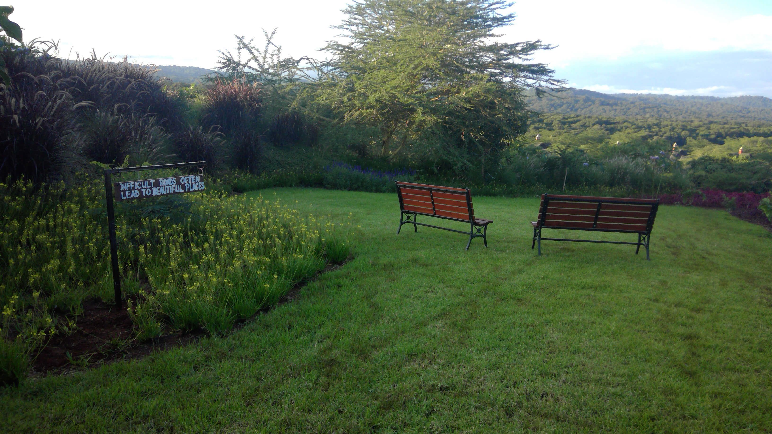 A grassy area with two benches and a sign.
